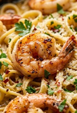 Ultra close-up macro food photography of creamy garlic butter shrimp pasta with seared jumbo shrimp in a cast-iron skillet