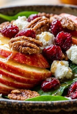 Ultra close-up macro food photography of autumn harvest honeycrisp apple salad with sliced red apples, candied pecans, cranberries, and goat cheese