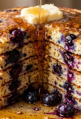 Ultra close-up macro of a tall stack of fluffy buttermilk blueberry pancakes with melting butter and warm maple syrup drip
