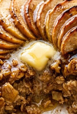 Ultra close-up macro food photography of cozy spiced apple cinnamon baked oatmeal with caramelized apple fan, toasted pecans, and melting butter