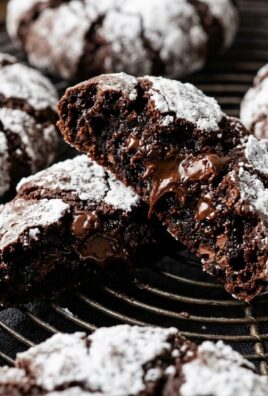 Ultra close-up macro of fresh-baked chocolate fudge crinkle cookies with snowy powdered sugar crackles and molten chocolate center
