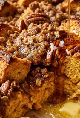 Ultra close-up macro food photography of overnight pumpkin brioche french toast casserole with caramelized brown sugar pecan streusel and maple syrup