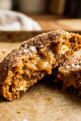 Ultra close-up macro food photography of soft brown butter pumpkin snickerdoodle cookies broken open with gooey spiced center and flaky salt