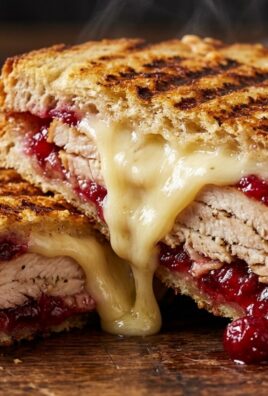 Ultra close-up macro of warm turkey cranberry brie panini with melted gooey brie cheese oozing between crisp sourdough bread